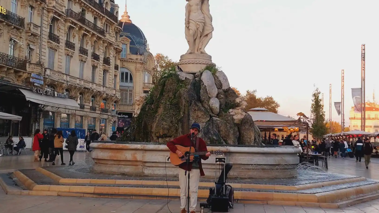 Un guitariste fait de la musique devant la fontaine Place de la Comédie à Montpellier.